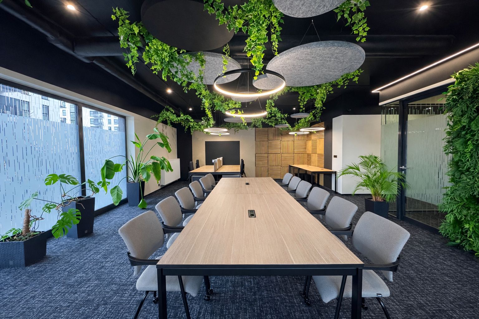 Conference table with chairs under plants and round lamps