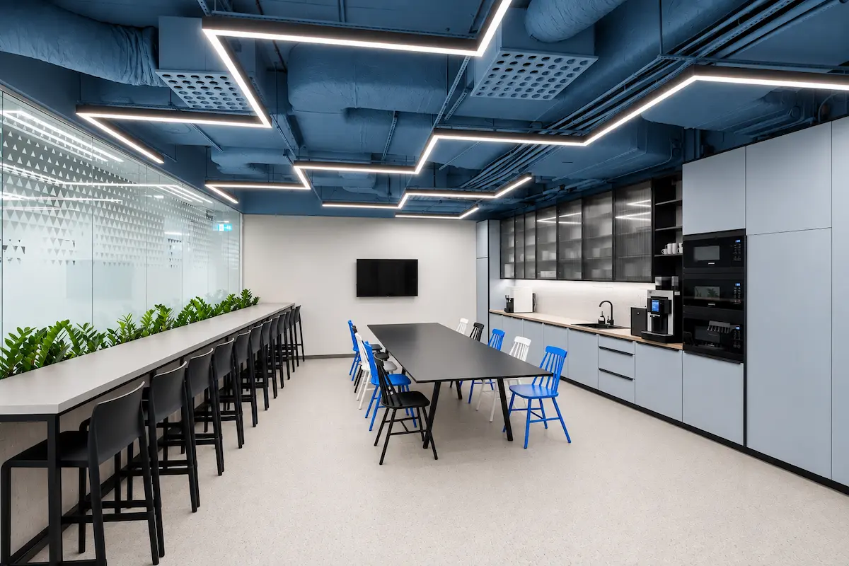 Modern office kitchen with a blue ceiling and communal table